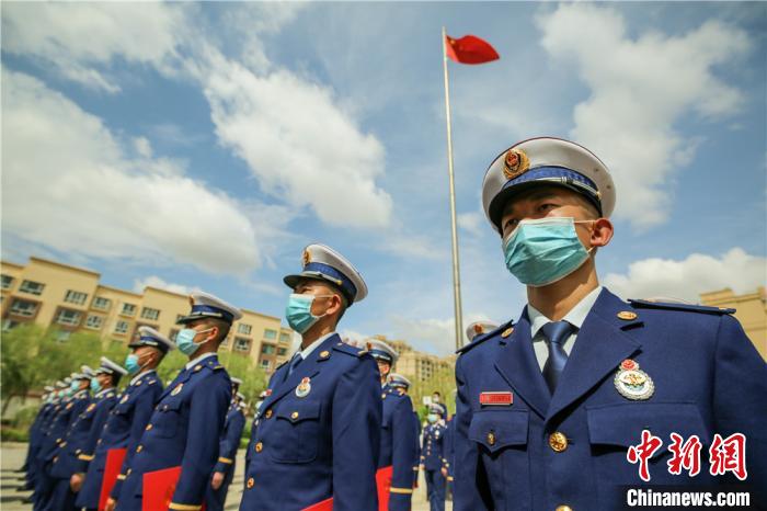 图为佩戴消防救援衔的新消防员在国旗下整齐列队 张小军 摄